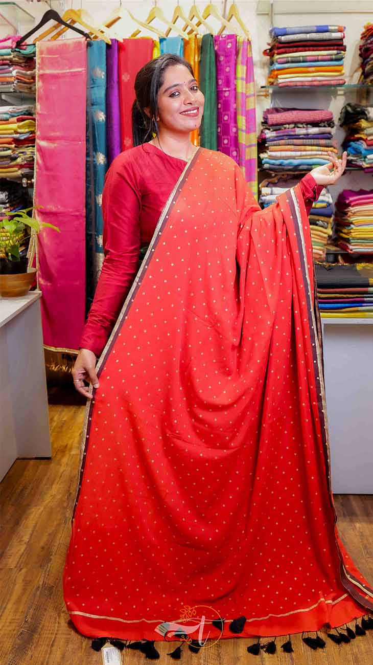Woman holding a red saree with a colorful background of fabrics