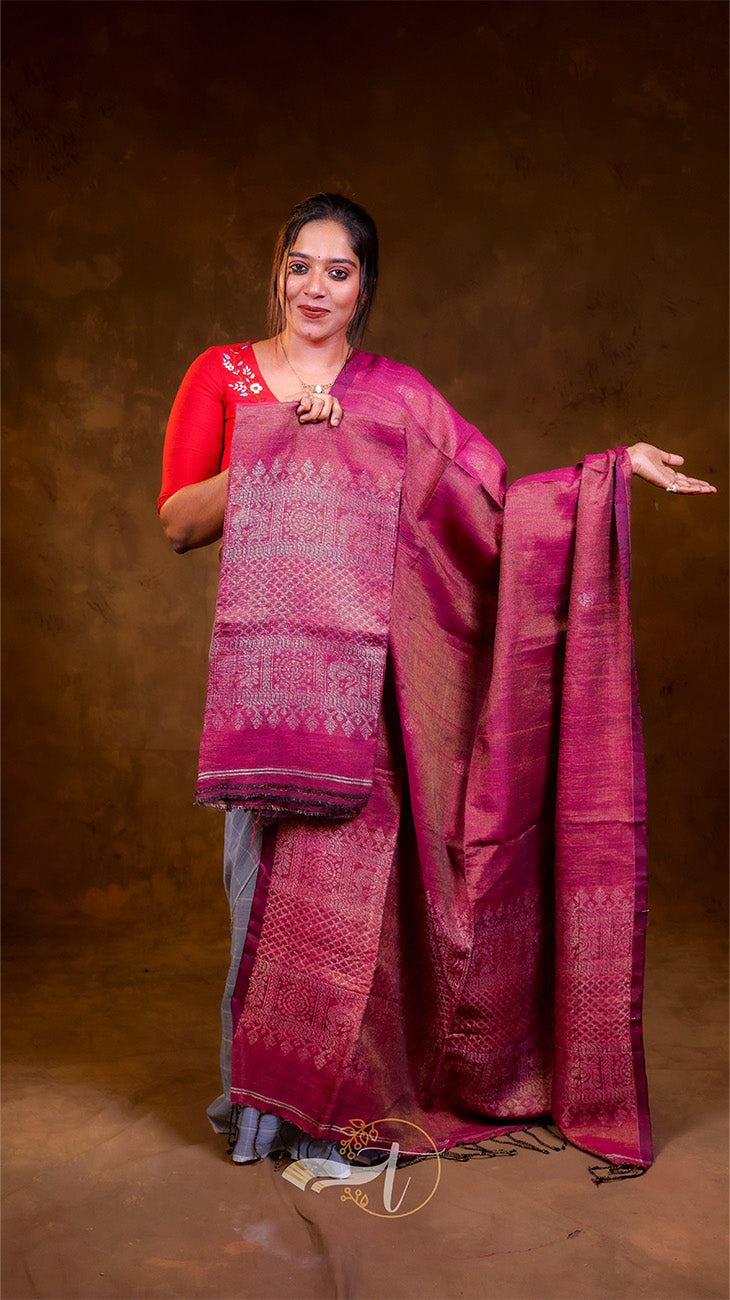 Woman wearing a pink saree with a red blouse against a brown background