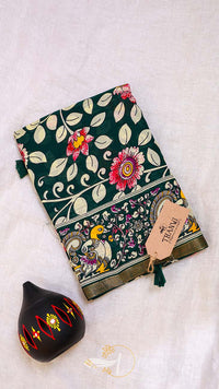 Decorative notebook with floral design and a small black pot on a light background