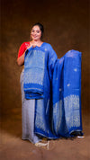 Woman holding a blue and gray saree with a brown background