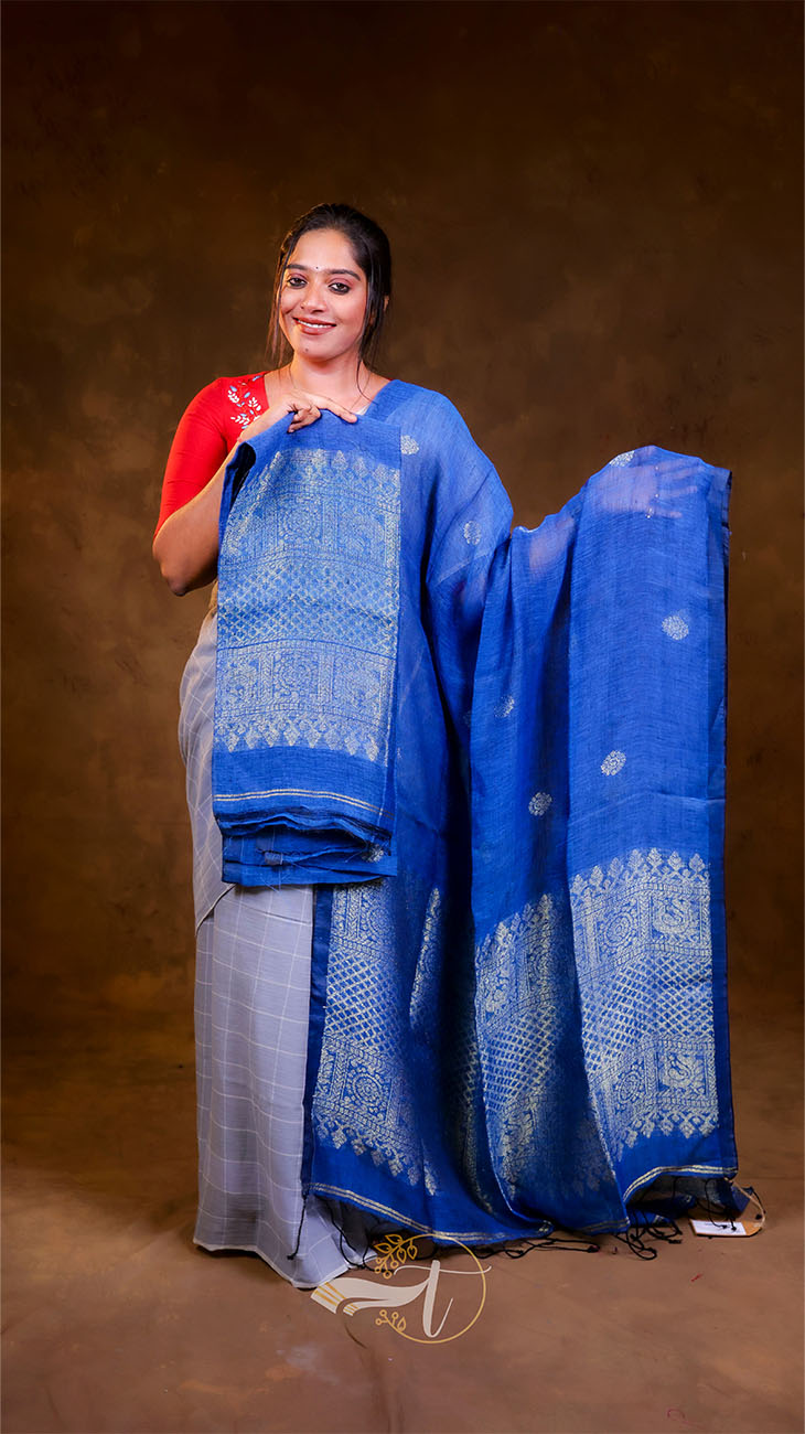 Woman holding a blue and gray saree with a brown background