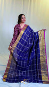 Woman wearing a blue saree with a gold border against a white background