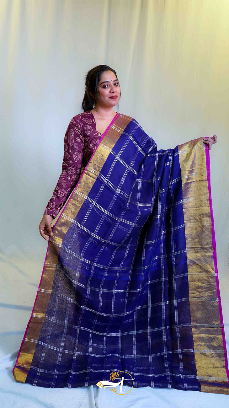 Woman wearing a blue saree with a gold border against a white background