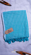 Turquoise checkered towel with tassels on a light gray background