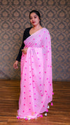 Woman wearing a pink saree with heart patterns against a patterned wall.