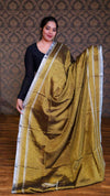 Woman wearing a gold saree with a patterned background