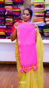 Woman holding a pink fabric with tassels in front of colorful fabric displays.