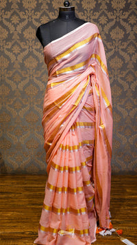 Pink saree with gold stripes on a mannequin against a patterned wall.