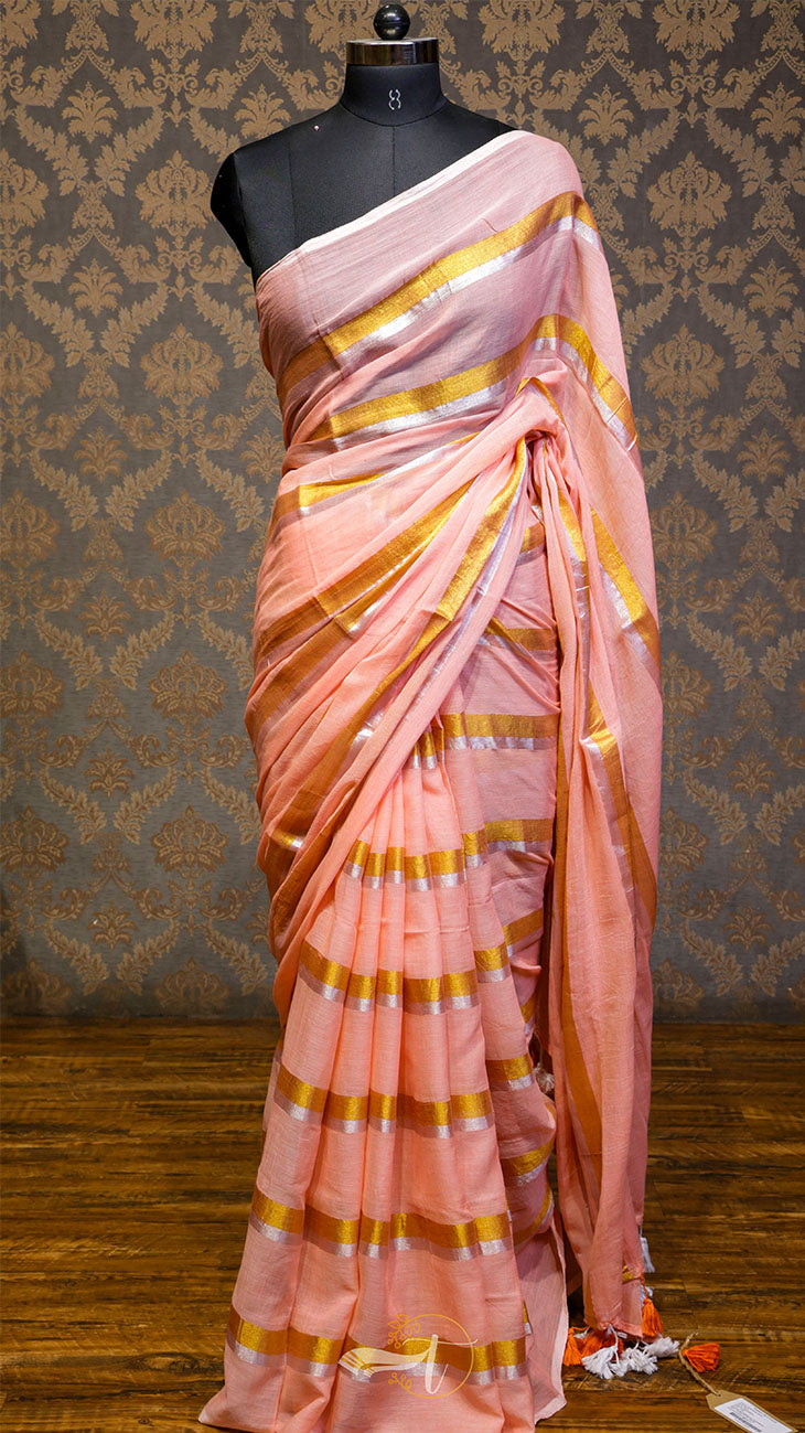Pink saree with gold stripes on a mannequin against a patterned wall.
