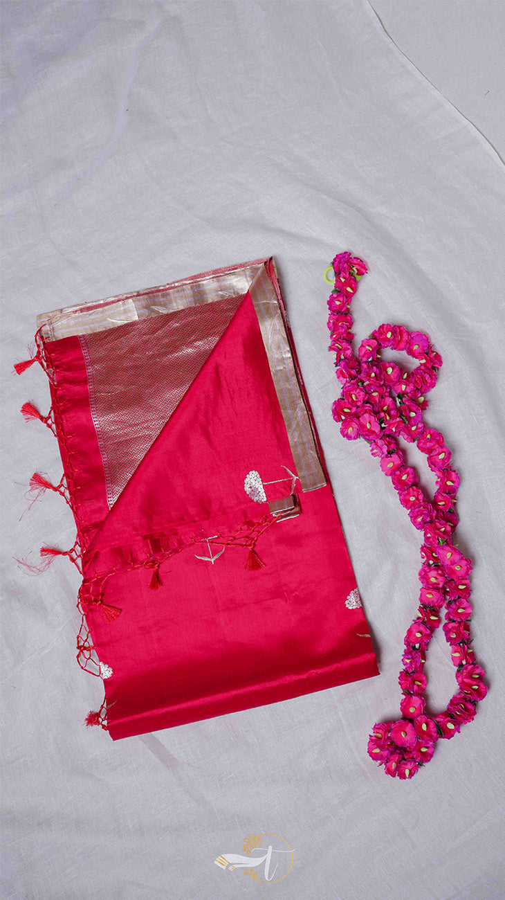Red saree with gold border and pink beaded necklace on a light gray background