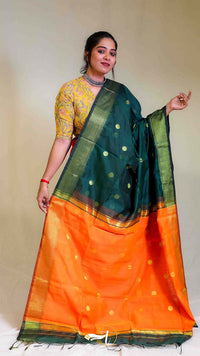 Woman wearing a green and orange saree with a plain background