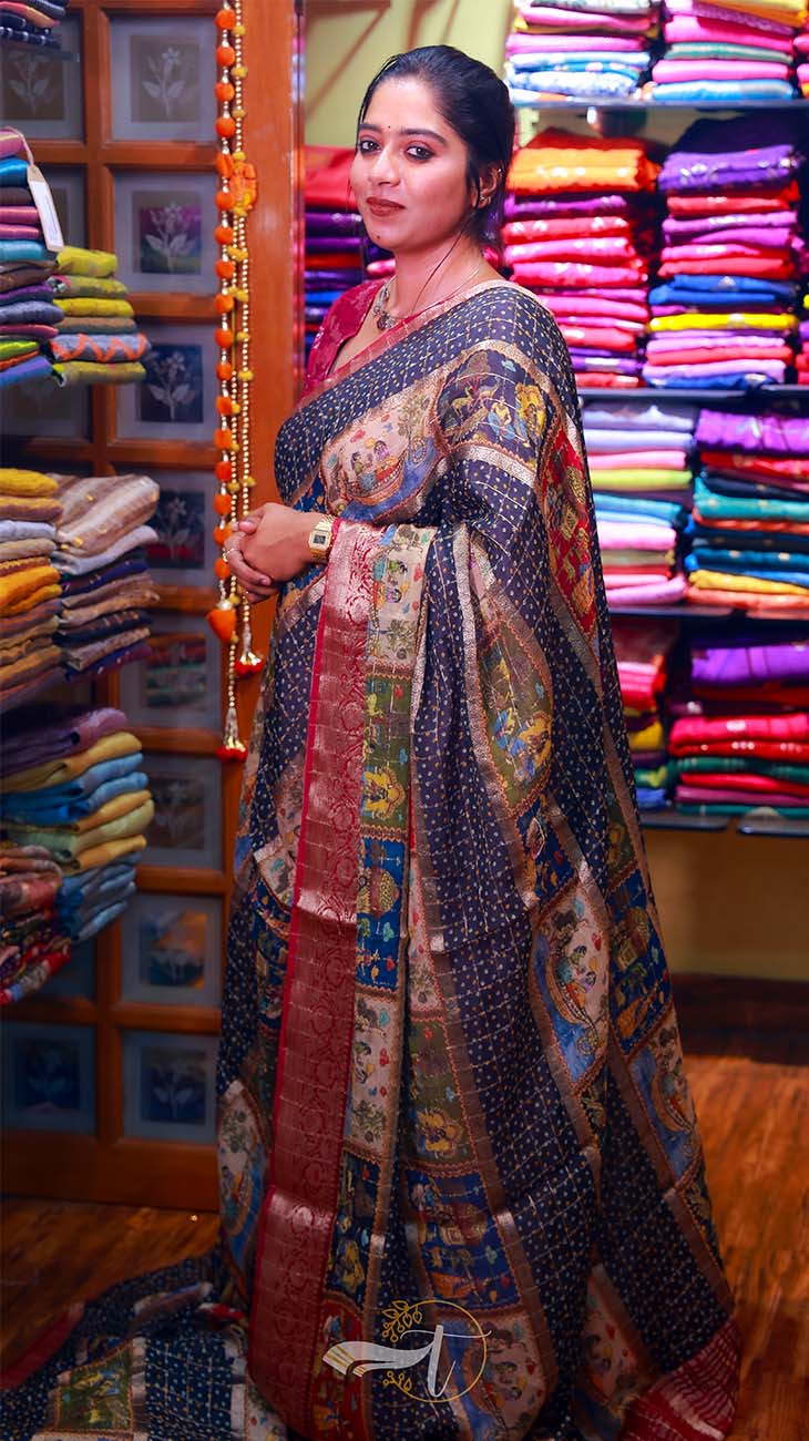 Woman in a colorful saree standing in front of a display of fabric