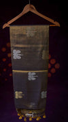 Dark fabric with embroidered patterns on a wooden hanger against a dark background