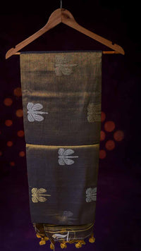 Dark fabric with embroidered patterns on a wooden hanger against a dark background