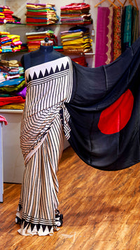 Saree with black and white pattern draped over a mannequin in a fabric store.