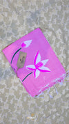Pink towel with white floral design and brand tag on a textured surface