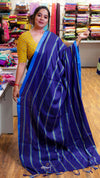 Woman wearing a blue saree with a yellow blouse in a fabric store.