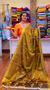 Woman holding a yellow saree in a fabric store with colorful sarees on shelves.