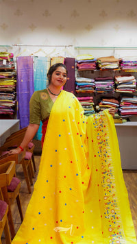 Woman in a yellow saree with colorful polka dots in a fabric store.