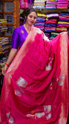 Woman wearing a bright pink saree with a traditional blouse in a fabric store.