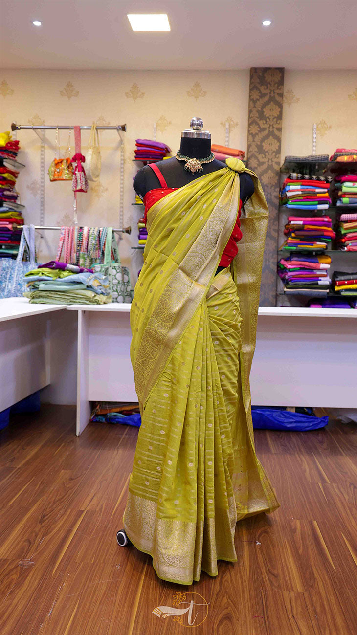 Mannequin wearing a yellow saree with a red blouse in a store setting.