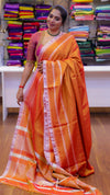 Woman wearing an orange saree with a white border in a store setting.