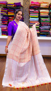 Woman holding a white saree with red and orange stripes in a fabric store.