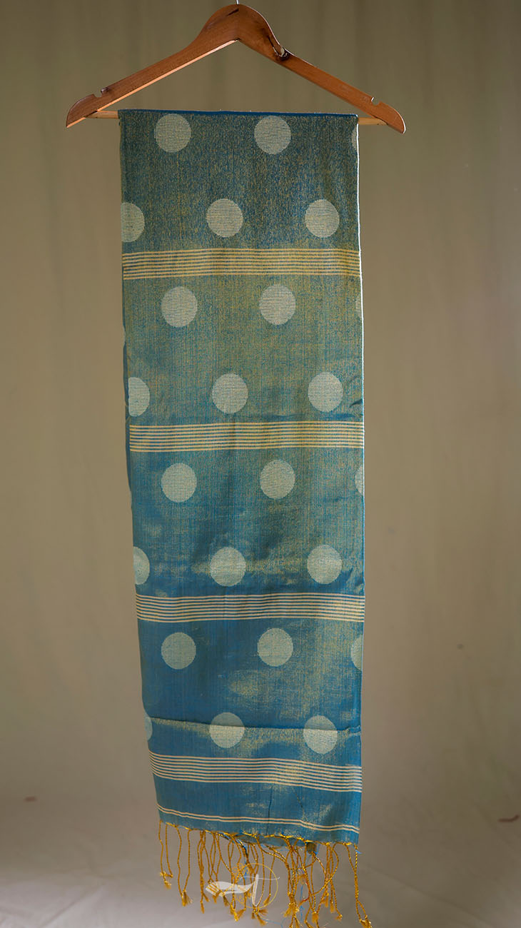 Blue fabric with white polka dots and gold accents hanging on a wooden hanger against a beige background.