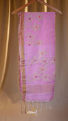 Pink scarf with floral patterns hanging on a wooden hanger against a beige curtain background