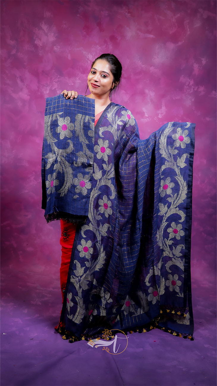 Woman holding a blue embroidered saree against a purple background