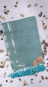 Teal scarf with tassels on a light background