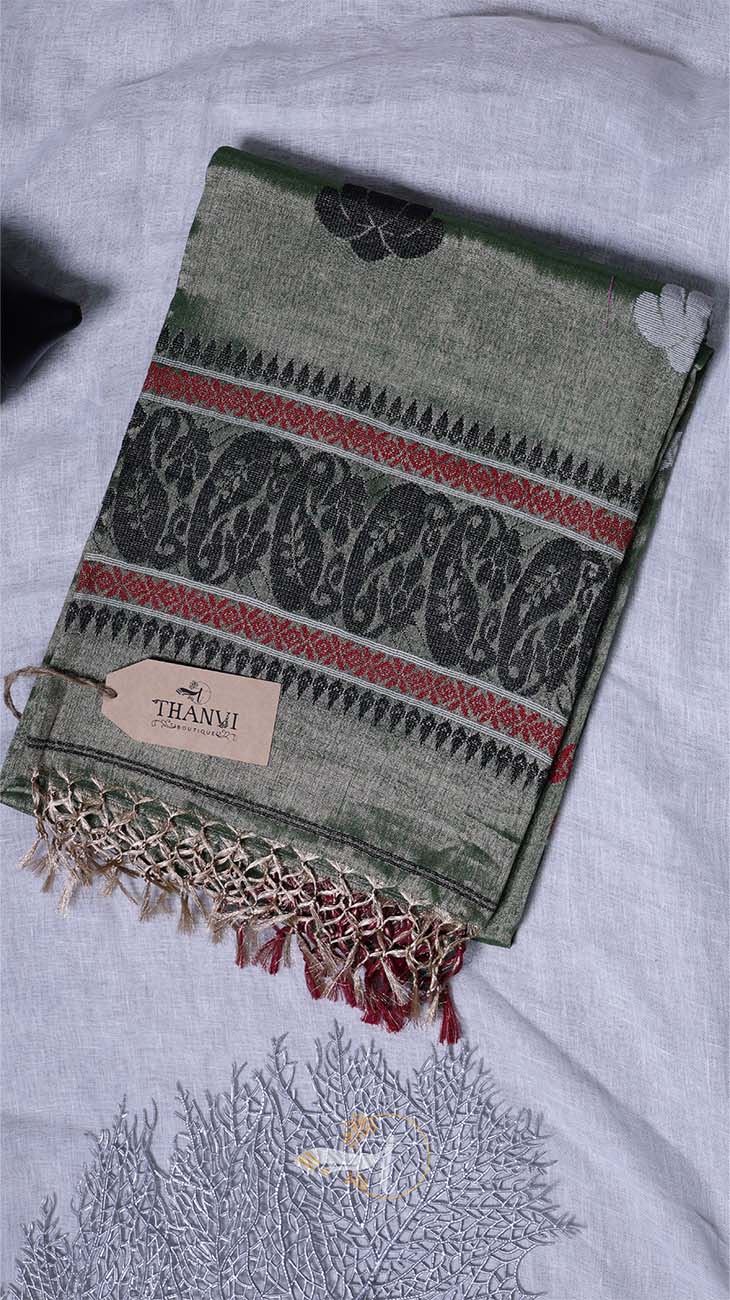 Green patterned scarf with tassels on a white surface, featuring a visible brand tag.