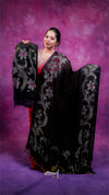 Woman holding a black embroidered saree against a purple background