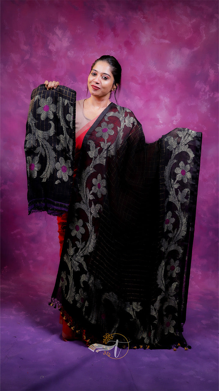 Woman holding a black embroidered saree against a purple background