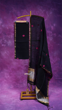 Black saree with pink floral patterns on a wooden stand against a purple background