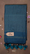 Blue striped towel with tassels on a brown background, featuring a 'THANU' tag.