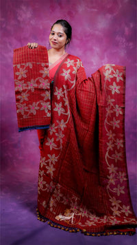 Woman wearing a red saree with white floral patterns against a purple background