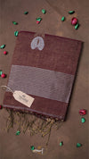 Brown towel with white logo and fringes on a brown background