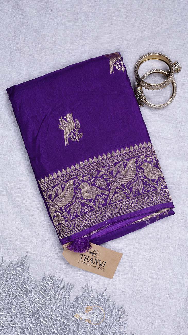 Purple saree with bird patterns and a 'THANVI' tag on a light gray background