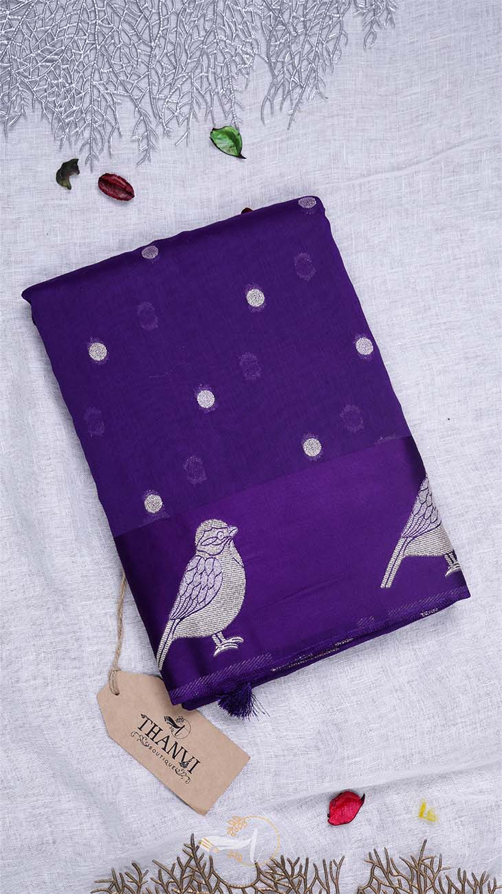 Purple fabric with bird patterns and a tag on a light gray background