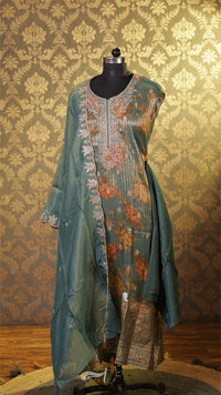 Teal embroidered kurta on a mannequin against a patterned wall.
