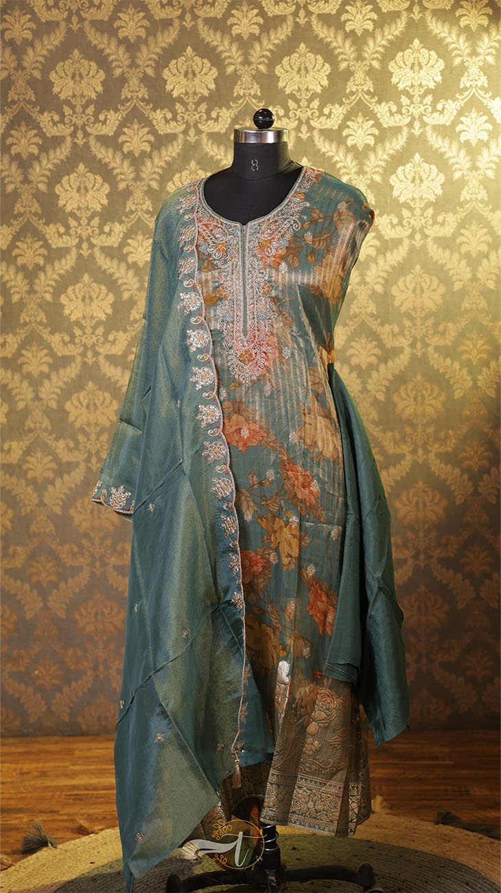 Teal embroidered kurta on a mannequin against a patterned wall.