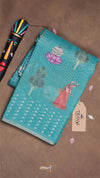 Teal pouch with floral designs on a brown surface