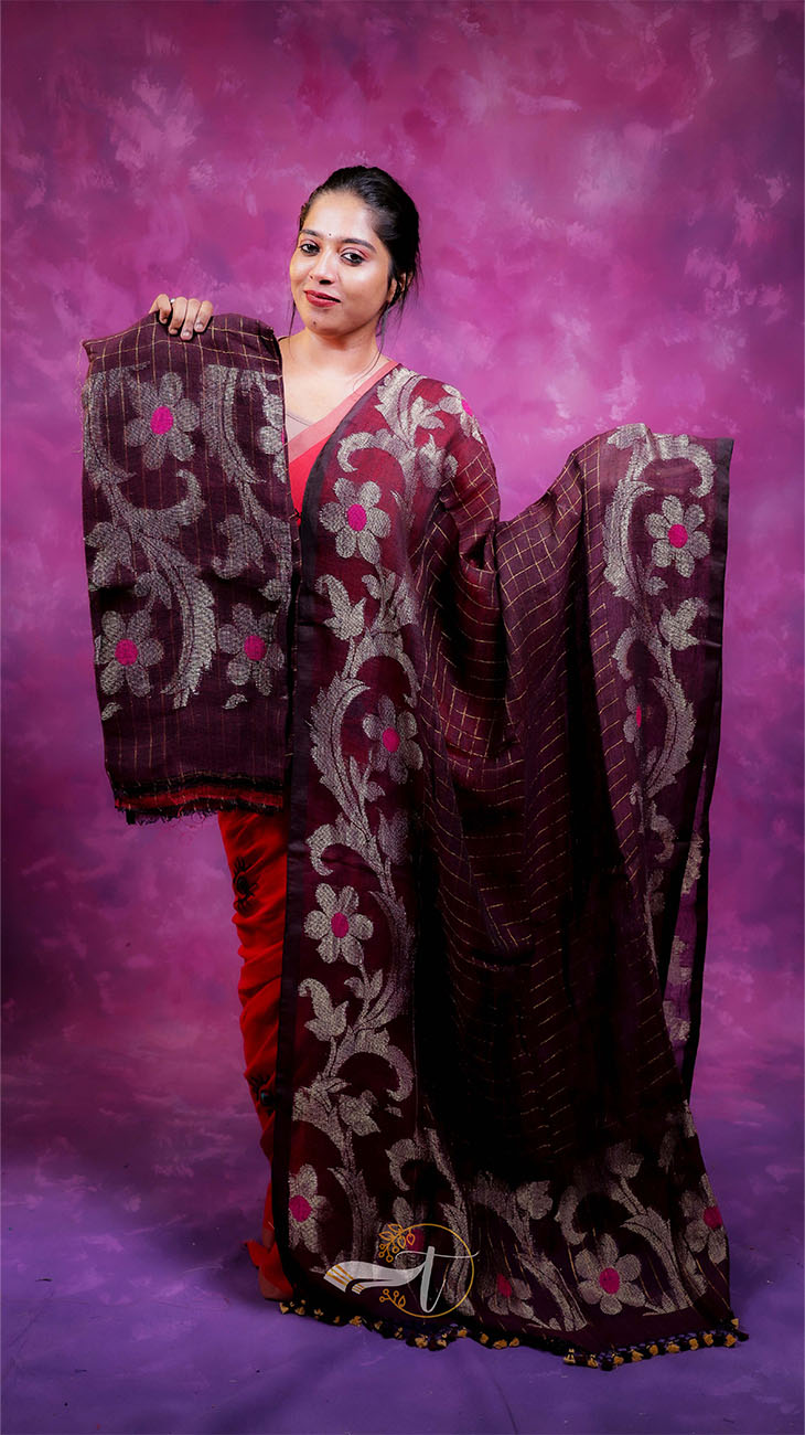 Woman holding a maroon saree with floral patterns against a purple background