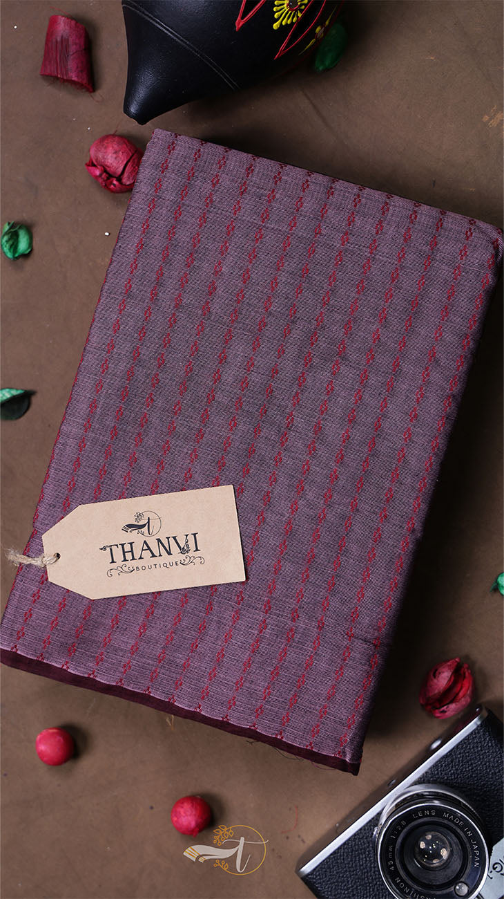 Plaid fabric with a 'THANVI' tag on a brown surface with decorative items.