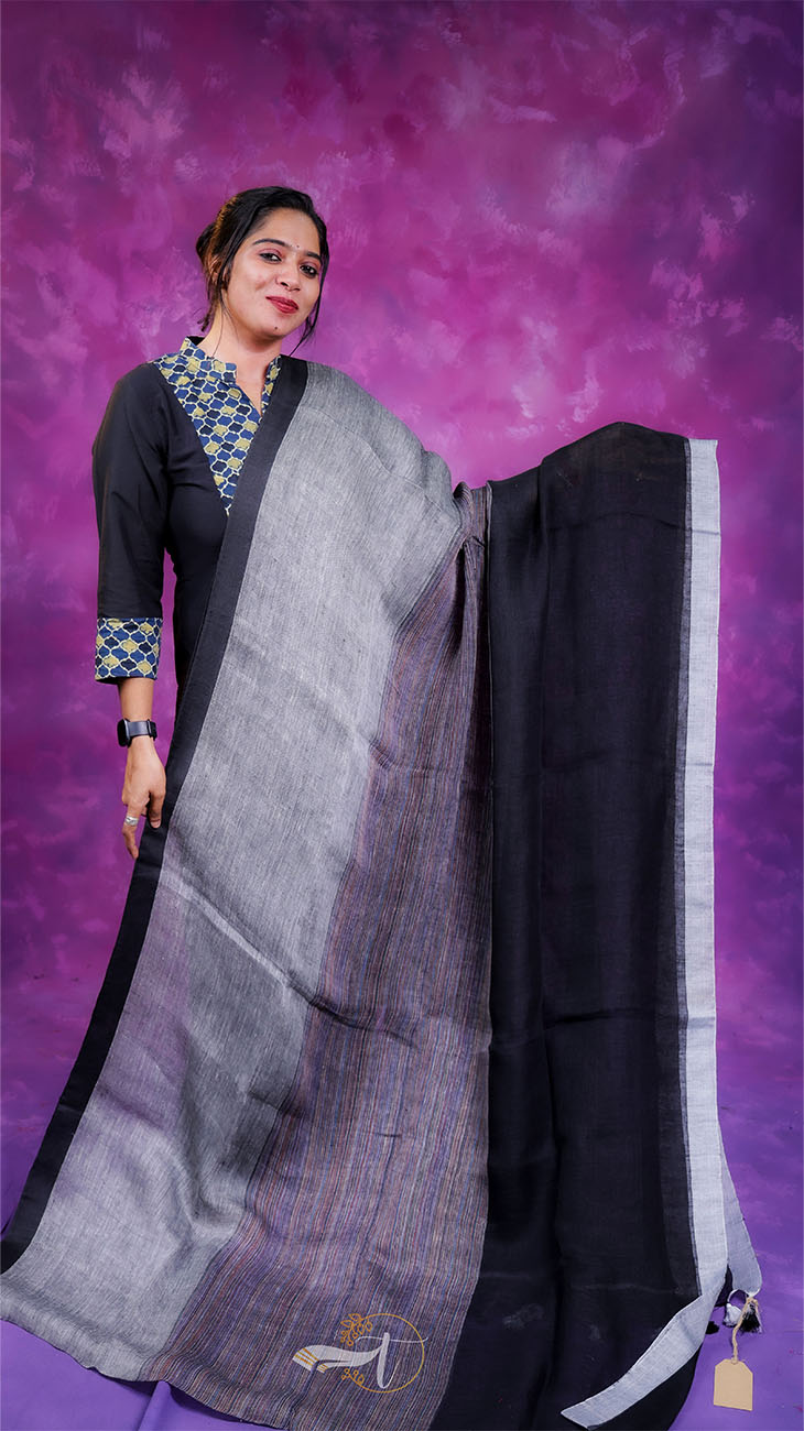 Woman holding a black and gray saree against a purple background