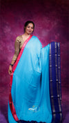 Woman wearing a blue saree with a pink border against a purple background