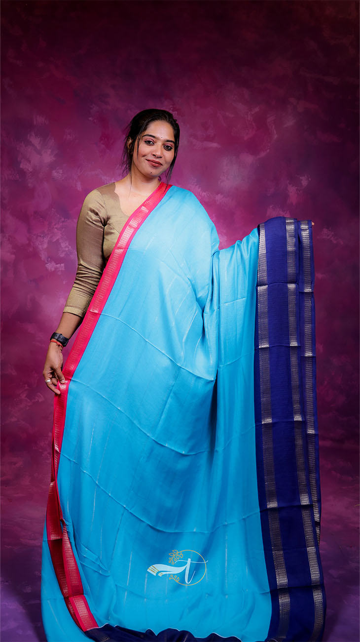 Woman wearing a blue saree with a pink border against a purple background