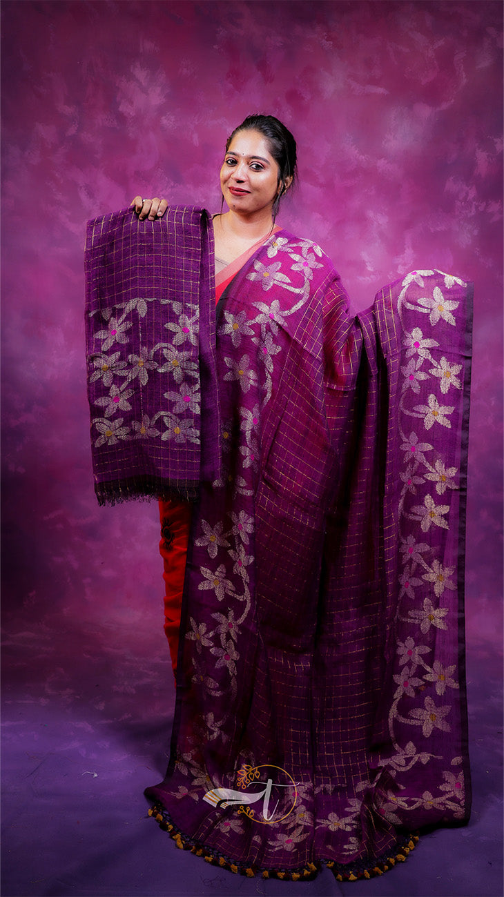 Woman holding a purple saree with floral patterns against a purple background