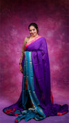 Woman wearing a purple and blue saree against a pink background
